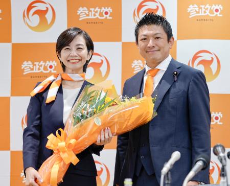 比例代表で当選を決めた梅村みずほ氏（左）に花束を渡した参政党の神谷代表＝２０日午後８時２５分、東京都新宿区