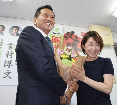大阪選挙区で当選を決め、花束を受け取る日本維新の会の岡崎太氏＝２０日夜、大阪市東成区