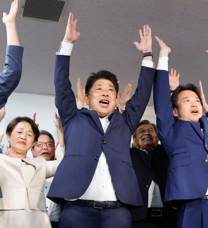 福岡選挙区で当選を決め、万歳する公明党の下野六太氏（中央）＝２１日未明、福岡市