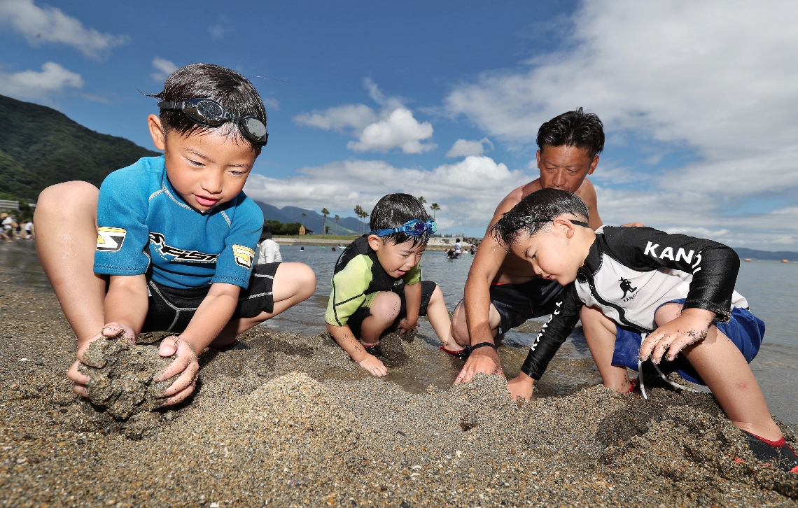 照りつける日差しの下、砂遊びを楽しむ家族連れ＝２１日、大分市神崎の田ノ浦ビーチ