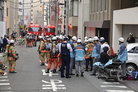 ３月、東京都千代田区のビル解体現場近くに集まる消防隊員ら。作業員１６人がＣＯ中毒となり病院に搬送された