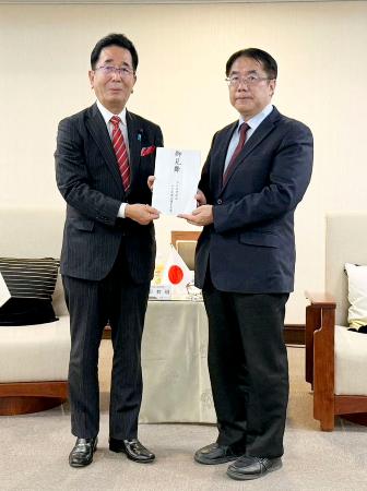 ２３日、台湾・台南市で黄偉哲市長（右）に見舞金を手渡す、日台友好促進山口県議会議員連盟の島田教明会長（野崎孝男・台湾行政院政務顧問提供、共同）
