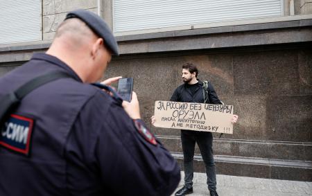 ロシア下院付近で、「過激派」サイト検索に罰金を科す法案に抗議する男性を撮影する治安当局者＝２２日、モスクワ（ロイター＝共同）