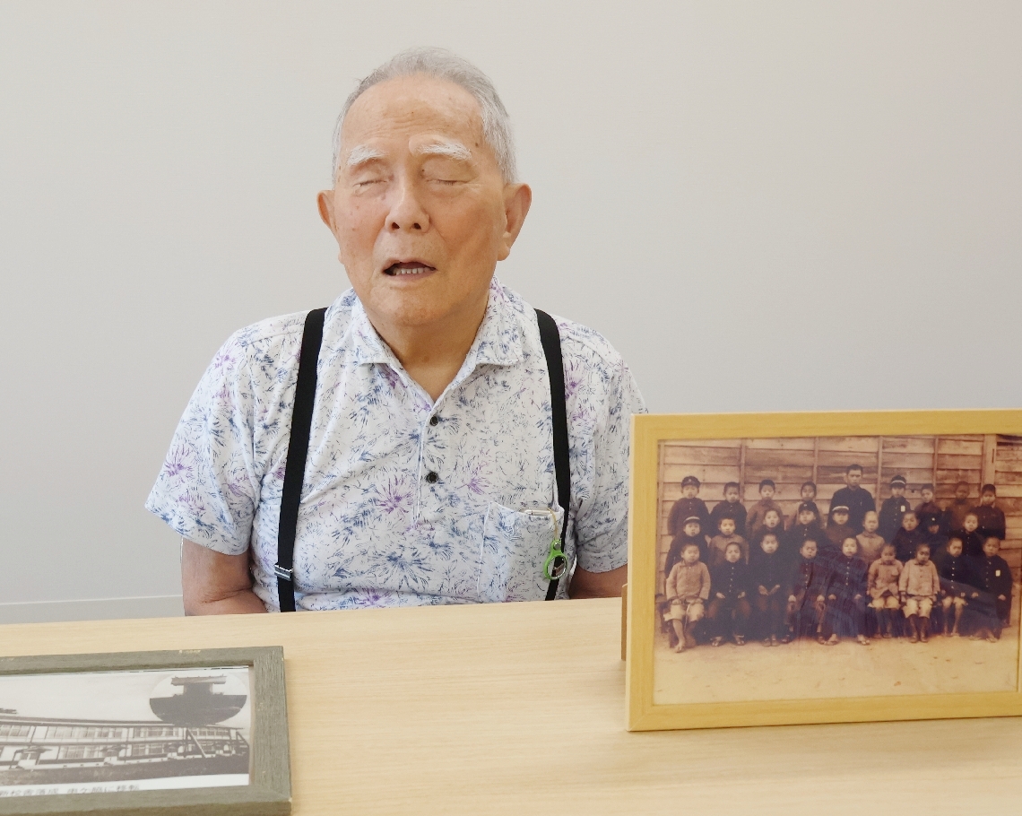 空襲の体験を語る西田菊人さん。目が不自由になった今も同級生の集合写真を大切にしている＝２２日、豊後大野市三重町内田