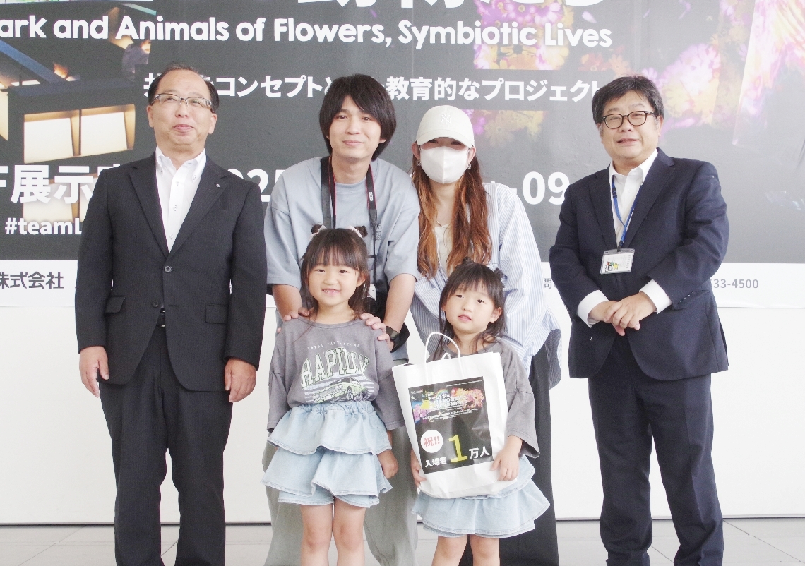 １万人目の記念品を受け取った小野茉衣花ちゃん（前列右）＝２５日、大分市寿町の県立美術館
