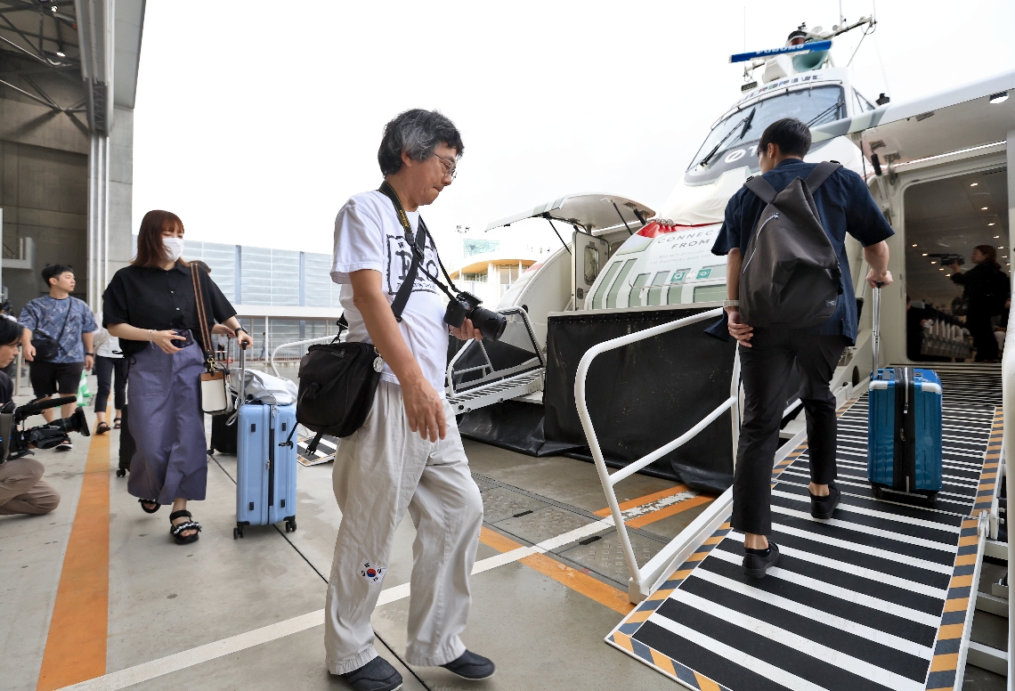 大分港西大分地区から出る第１便に乗り込む人たち＝２６日午前６時３９分、大分市駄原