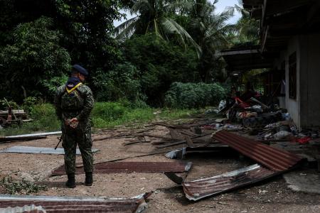 ２５日、タイ・スリン県で被害を受けた民家のそばに立つタイ軍の兵士（ゲッティ＝共同）