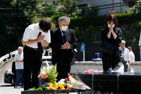津久井やまゆり園の「鎮魂のモニュメント」に献花し、手を合わせる人たち＝２６日午前、相模原市