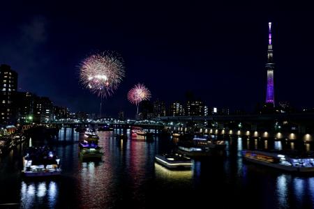 東京・隅田川花火大会で打ち上げられた花火。右は東京スカイツリー＝２６日夜（多重露光）