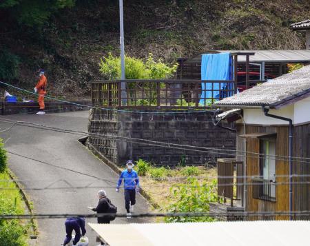 強盗殺人事件の現場となった民家（右奥）の周辺を調べる捜査員＝２７日午前、佐賀県伊万里市