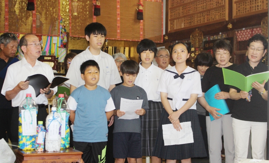 追悼曲「あの日を忘れない」を歌う参列者＝津久見市保戸島の海徳寺