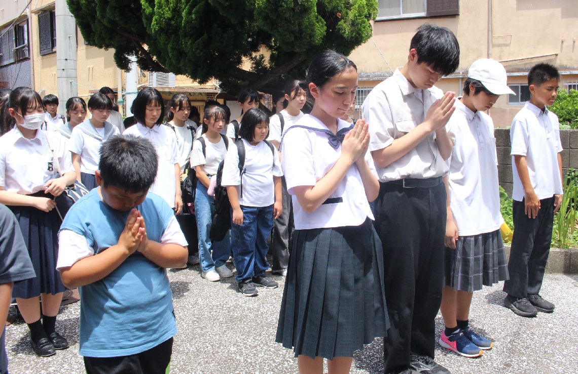慰霊碑の前で手を合わせる子どもたち＝津久見市の保戸島小・中