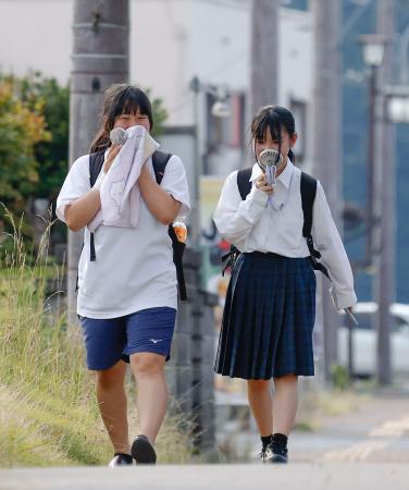 小型扇風機を手に兵庫県丹波市柏原町地区を歩く人たち。国内最高気温を更新した＝３０日午後