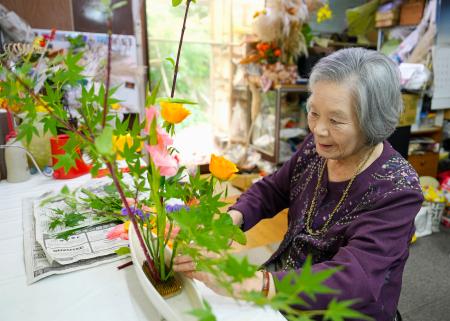 ＪＲ大村駅に飾るため、自宅で花を生ける笹山トヨ子さん＝５月、長崎県大村市