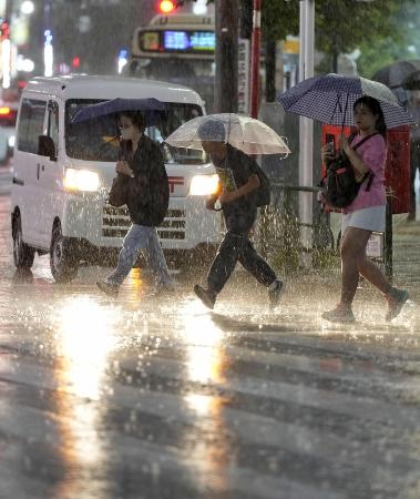 大雨の中、傘を差して歩く人たち＝１０日、東京・池袋