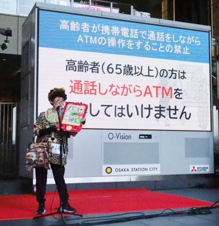 ＡＴＭの前で高齢者が携帯電話で通話するのを禁止した条例について、寸劇で説明する大阪府警の職員＝１日午後、大阪市北区