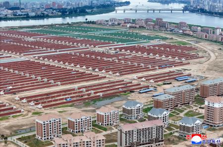 中朝国境の鴨緑江（奥）に面して建てられた住宅と建設中の大規模温室農場。１日に北朝鮮の金正恩朝鮮労働党総書記が視察した＝北朝鮮北西部・新義州（朝鮮中央通信＝共同）
