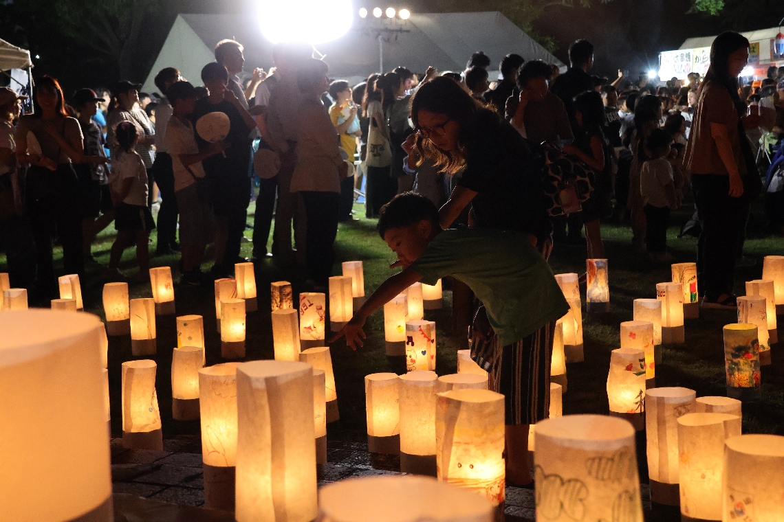 自分の作った紙灯籠を指さす児童とその保護者