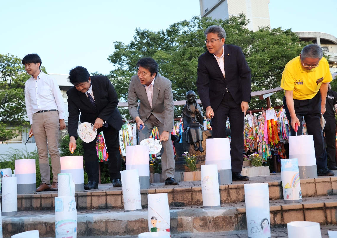 「ムッちゃん平和の灯」に火をともす足立信也市長ら