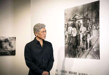 「被爆８０年企画展　ヒロシマ１９４５」を見学する歌手で俳優の吉川晃司さん＝２日、東京都目黒区の東京都写真美術館