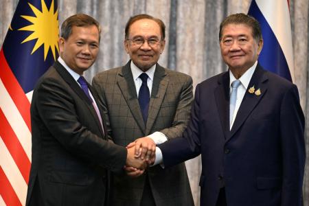 握手するタイのプムタム首相代行（右）、カンボジアのフン・マネット首相（左）と、仲介したマレーシアのアンワル首相＝７月、クアラルンプール近郊（ロイター＝共同）