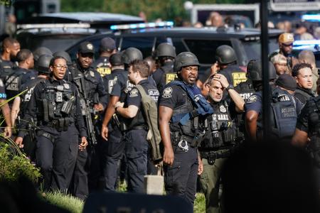 ８日、米南部アトランタにある疾病対策センター（ＣＤＣ）の施設で、銃撃事件の対応に当たる警察官ら（ゲッティ＝共同）