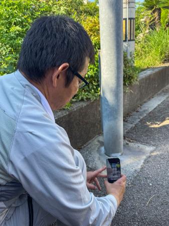 パナソニックが開発した、スマートフォンを使って街灯などの劣化具合を点検する新サービスの実演＝７月、愛媛県新居浜市