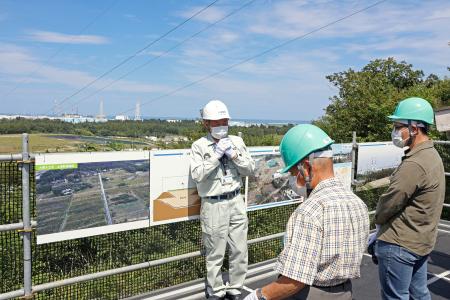 中間貯蔵施設を巡るバスツアーの参加者に説明する施設の職員（奥）＝９日午後、福島県大熊町