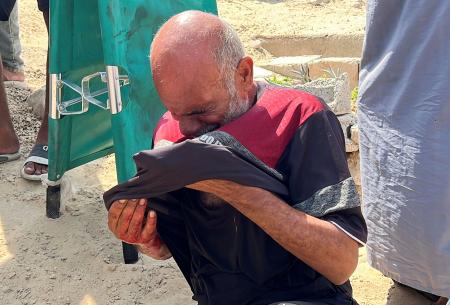 空中投下された物資が直撃し、死亡した少年の葬儀で嘆く父親＝９日、ガザ中部ヌセイラト（ロイター＝共同）