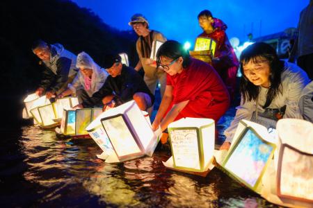 日航ジャンボ機墜落事故から４０年となるのを前に、「御巣鷹の尾根」の麓を流れる神流川に灯籠を流す人たち＝１１日夕、群馬県上野村