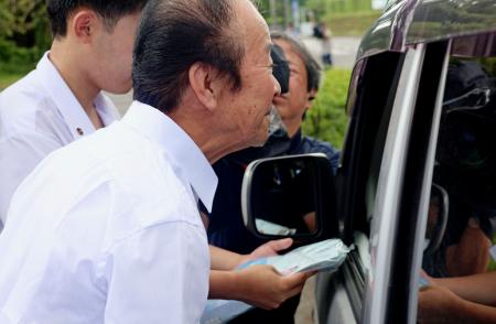 チラシを配って情報提供を呼びかける市川修一さんの兄健一さん＝１２日午前、鹿児島県日置市