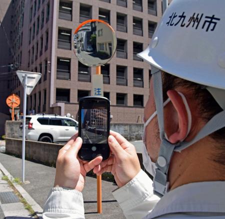 点検のためカーブミラーの写真を撮影する北九州市職員＝７月、北九州市