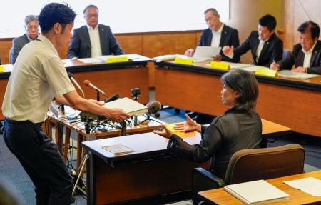 静岡県伊東市議会の百条委員会で証人尋問に応じ、確認のために東洋大の卒業アルバムを受け取る田久保真紀市長（右）＝１３日午前