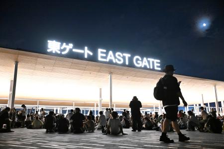 大阪メトロ中央線が運転見合わせとなり、万博会場で座り込む人たち＝１３日午後１１時２分、大阪市此花区の夢洲