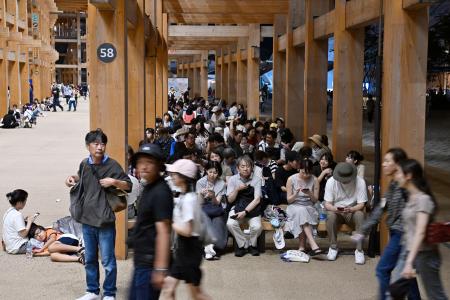 大阪メトロ中央線が運転見合わせとなり、万博会場で座り込む人たち＝１３日午後１１時３３分、大阪市此花区の夢洲