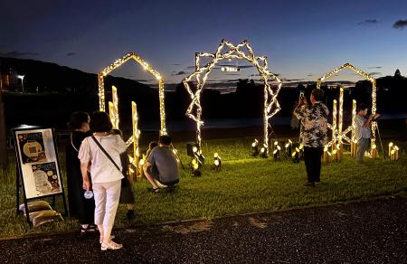 原鶴温泉に設置された竹製のオブジェを訪れた参加者ら＝７月、福岡県朝倉市（同県提供）