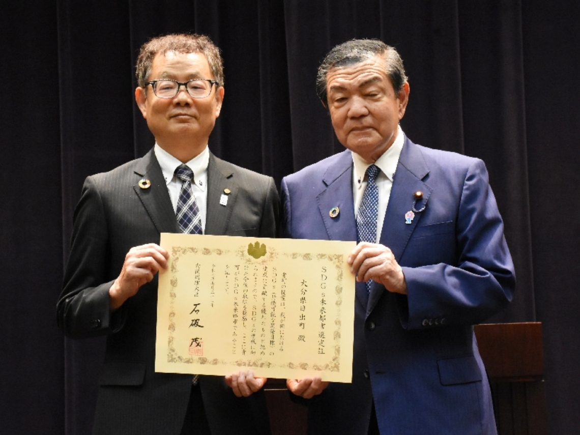 伊東良孝地方創生担当大臣（右）からＳＤＧｓ未来都市の選定証を受け取った日出町の大路正浩副町長＝７月２２日、東京