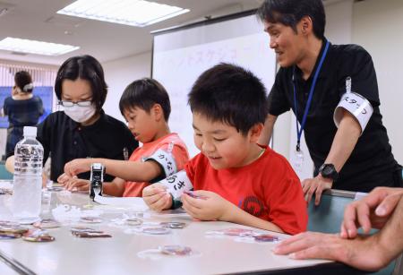 キッズインターンでバッジの袋詰めを体験する子どもたち＝１９日午後、相模原市