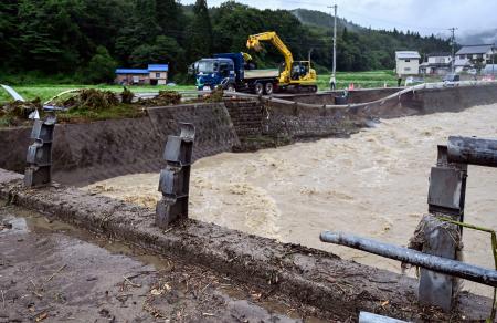秋田県仙北市で大雨のため壊れた桧木内川に架かる橋（手前）と崩れた道路（奥）＝２０日午後３時２５分