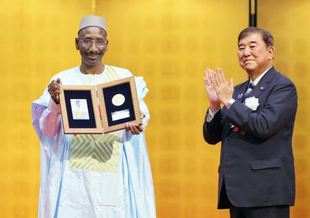 第５回野口英世アフリカ賞の授賞式で、石破首相（右）から拍手を送られるマリのアブドゥライ・ジムデ博士＝２２日夕、東京都港区の明治記念館（代表撮影）