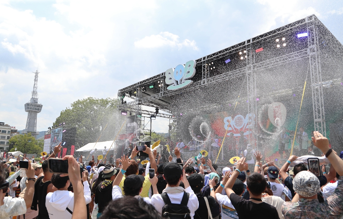 ステージ上から温泉が放水され、盛り上がる会場＝２３日、別府市のスパビーチ
