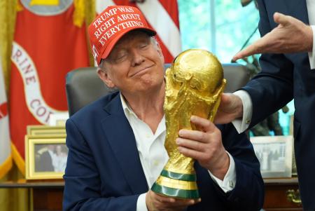 サッカーＷ杯組み合わせ抽選の日程発表で、優勝トロフィーを手にするトランプ大統領＝２２日、ワシントン（ＡＰ＝共同）