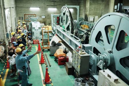 南海電鉄高野山駅で行われた「駅長おしごと体験」で、ケーブルカーの巻き上げ機を見学する子どもたち＝２３日午後