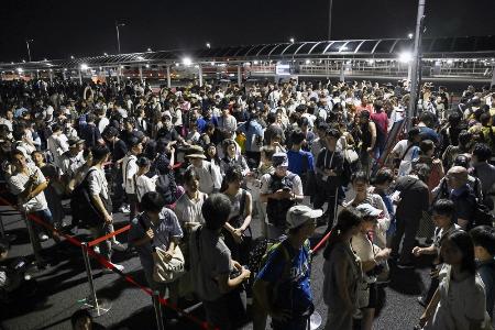 大阪メトロ中央線が運転見合わせとなり、タクシー待ちで西ゲート前に並ぶ大勢の人たち＝１３日、大阪市此花区の夢洲