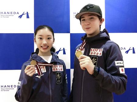 フィギュアスケートのジュニアＧＰシリーズ第１戦ラトビア大会から帰国し、金メダルを手に撮影に応じる中田璃士（右）と岡田芽依＝２５日、羽田空港