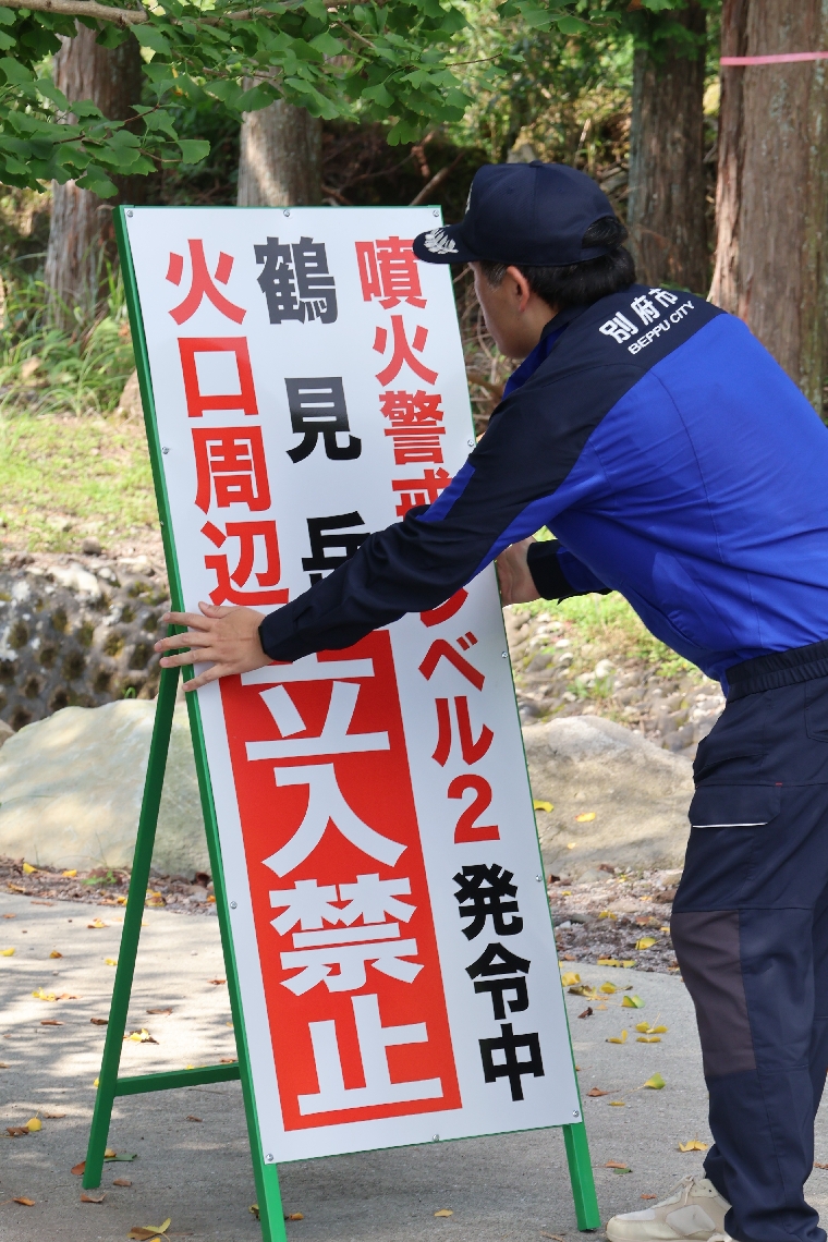 火口周辺への立ち入り禁止を知らせる看板を設置する別府市職員＝２６日、別府市
