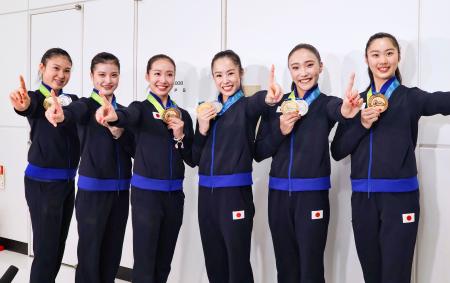 帰国した成田空港でポーズをとる新体操の世界選手権で団体総合初の金メダルを獲得した鈴木歩佳（中央右）ら日本代表＝２６日