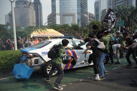警察に抗議しパトカーを襲撃する学生ら＝２９日、ジャカルタ（ＡＰ＝共同）