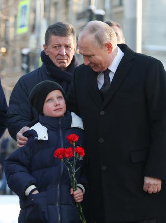 ロシア北西部サンクトペテルブルクを訪問し子供と話すプーチン大統領（右）。後ろに立つのがコザク大統領府副長官＝２月（タス＝共同）