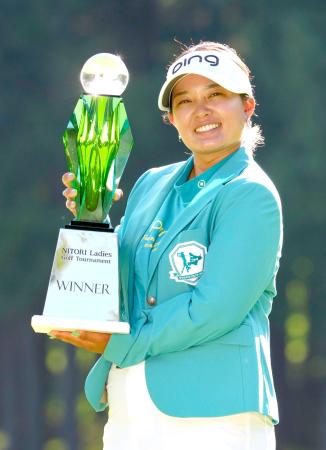 通算１２アンダーで優勝し、トロフィーを手に笑顔の鈴木愛＝北海道ＣＣ